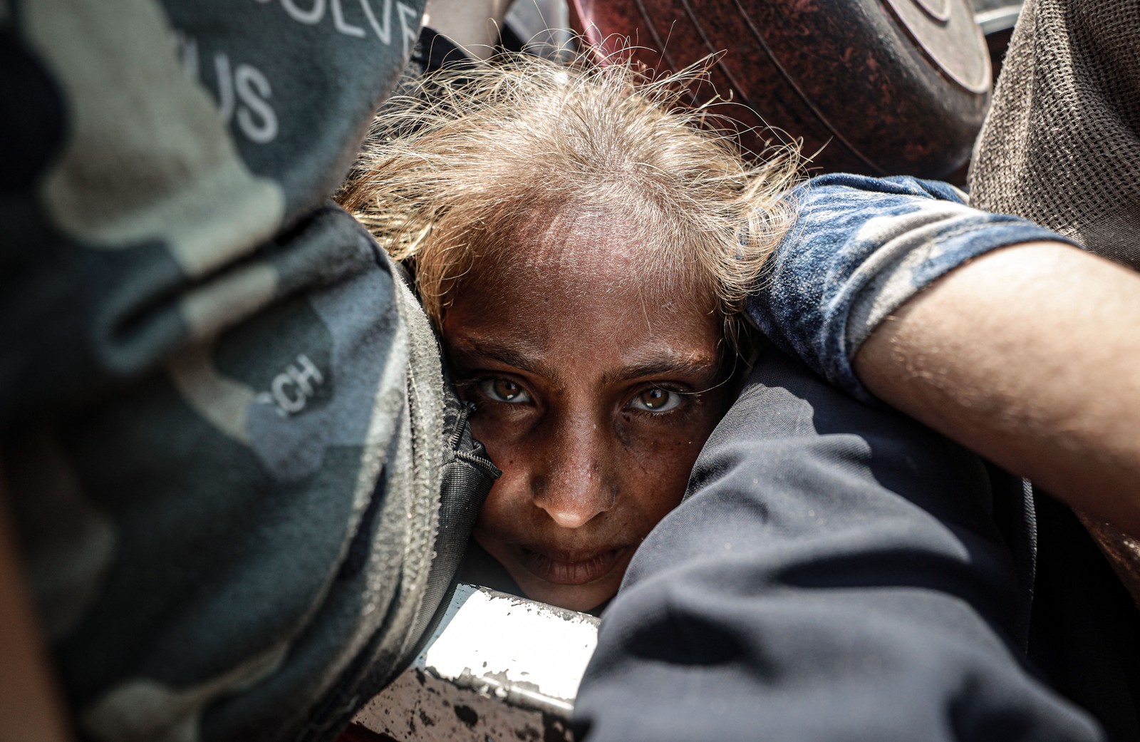 A close view of a child's face, smashed among other people in a crowd