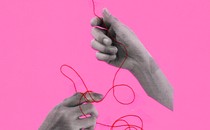 Three hands tangled in red string against a pink background
