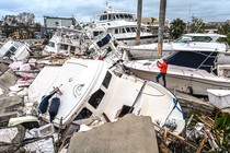 A person takes photos of piles of storm-damaged boats.