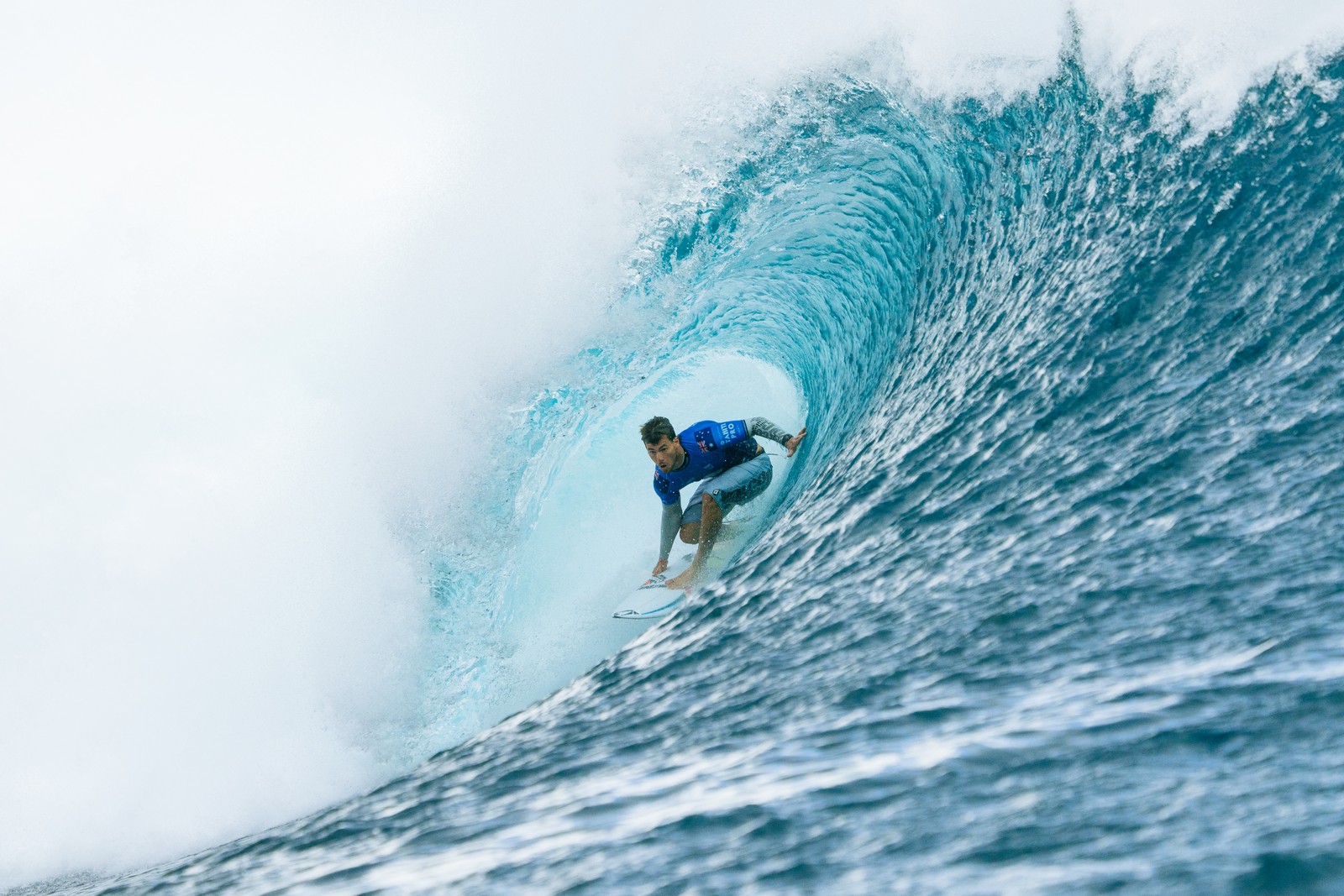 A surfer rides inside the barrel of a large wave.
