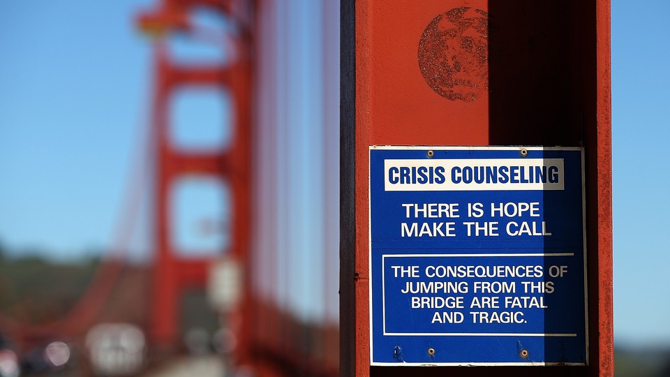 A blue and white sign attached to the Golden Gate Bridge that reads "There is hope, make the call"