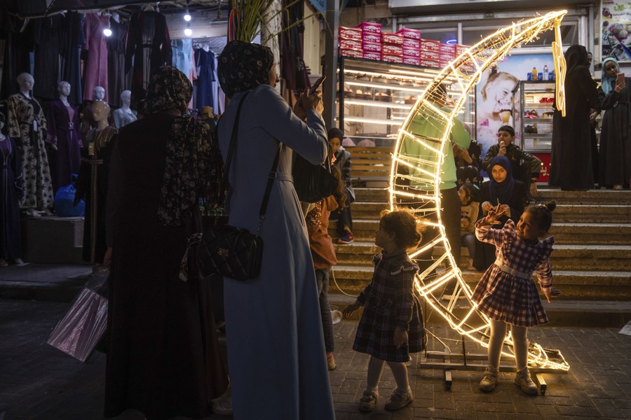 Μια γυναίκα φωτογραφίζει την κόρη της δίπλα σε μια διακόσμηση σε σχήμα μισοφέγγαρου σε μια αγορά.