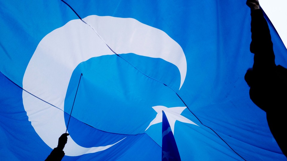 Hands holding a large Uyghur flag.
