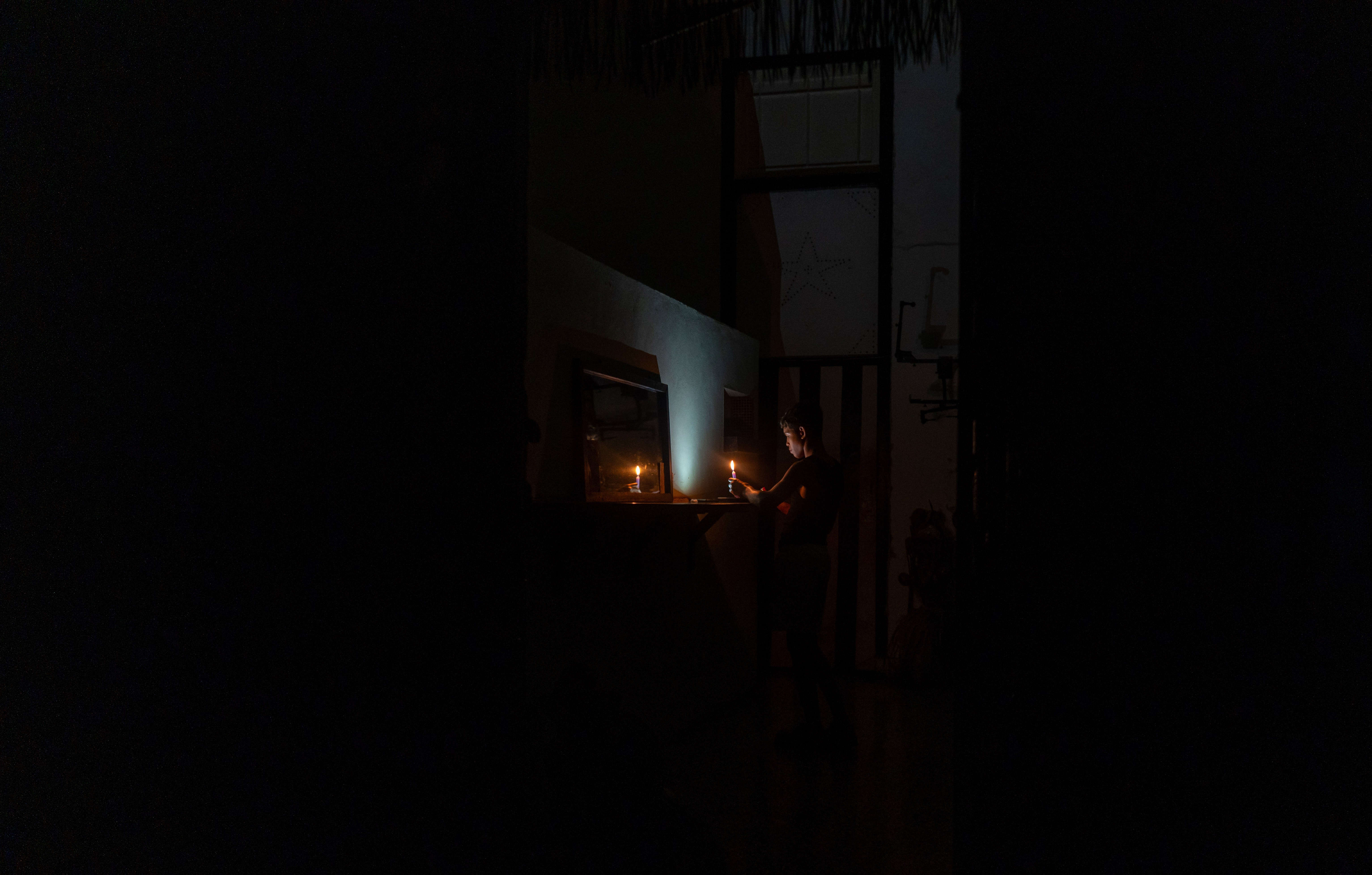 A person lights a candle during a blackout.
