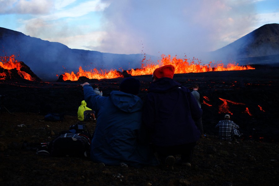 People sit near a lava flow.