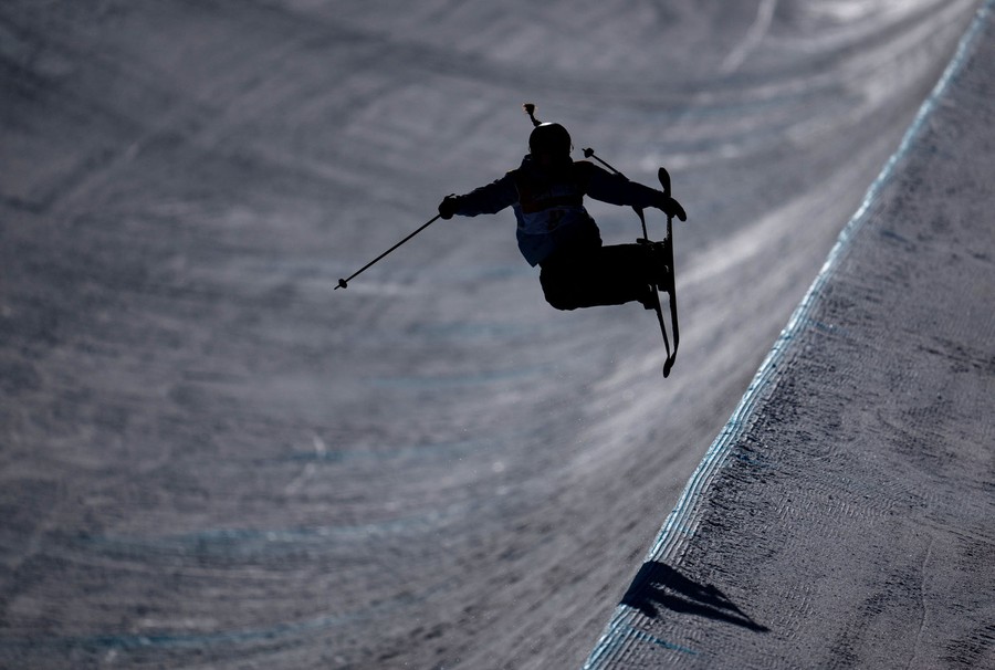 A skier makes a jump on a snow-covered halfpipe course.