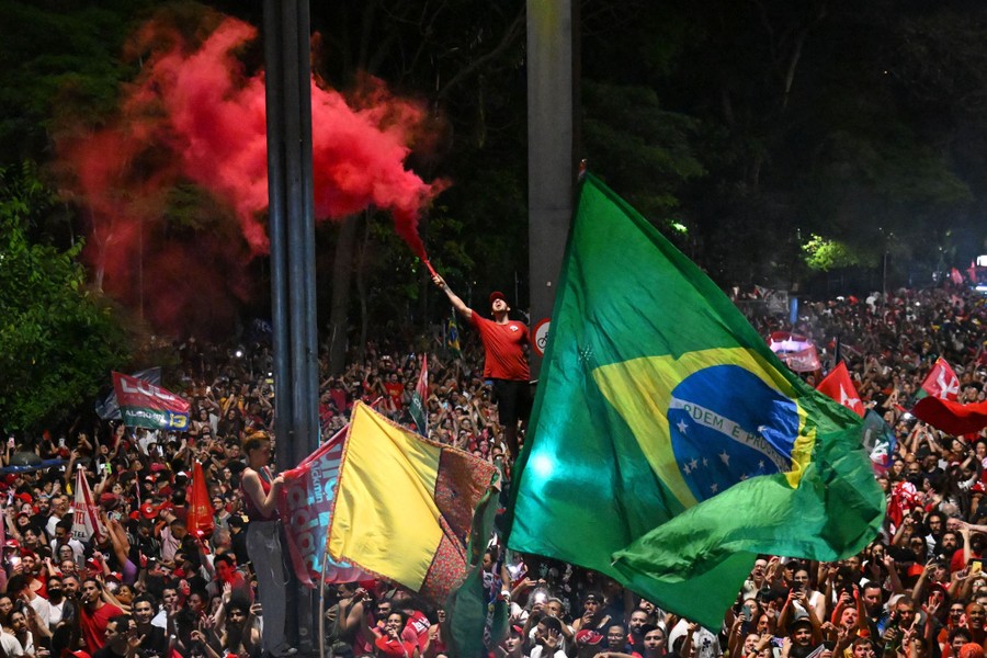 Një turmë brohorit ndërsa u mblodh në një rrugë, me një flamur të madh brazilian të valëvitur në qendër.