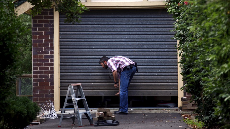 A man closes a garage door by hand.