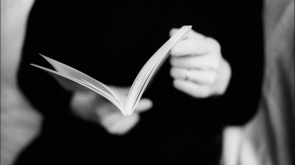 A black-and-white photo of a person reading a book