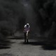 A protester crouching in black smoke