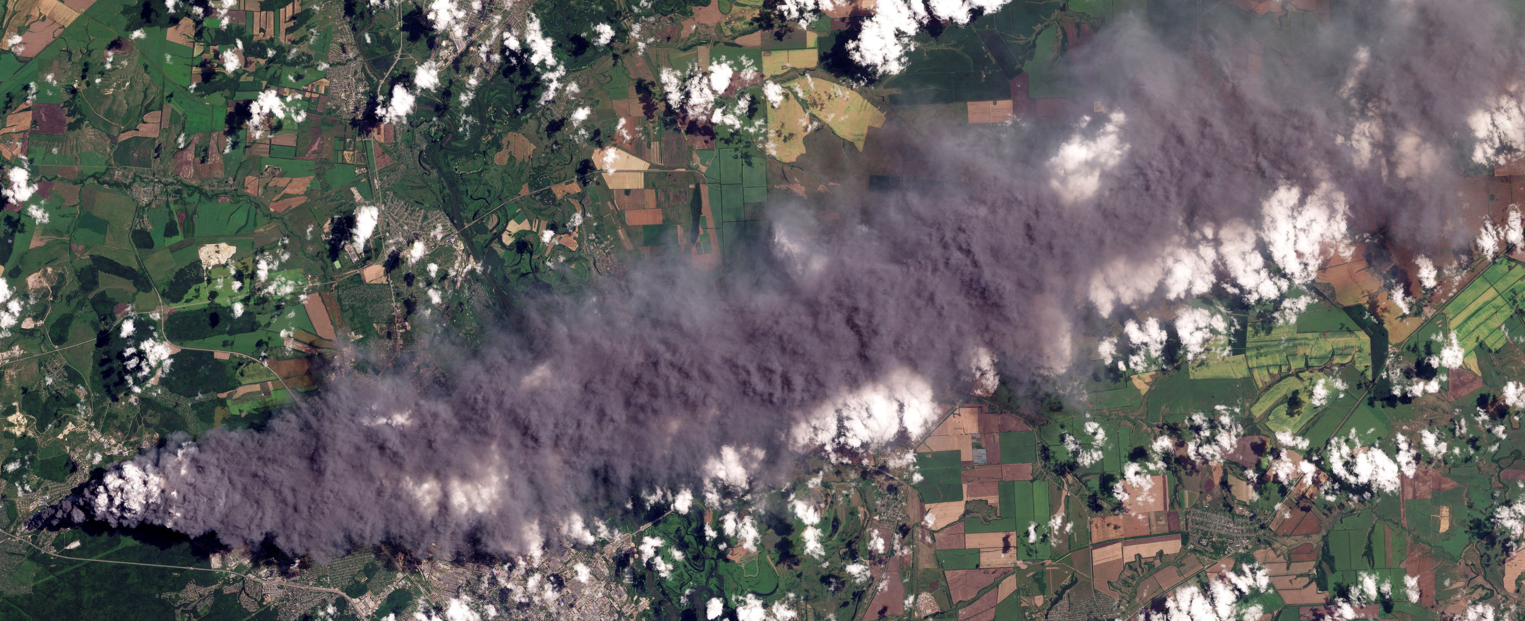 A satellite image shows smoke rising from a damaged warehouse.