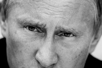 A black-and-white close-up of Vladimir Putin's face shows his eyes narrowed and his brow furrowed.