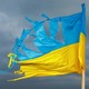 Photograph of a tattered Ukrainian flag flying in the wind