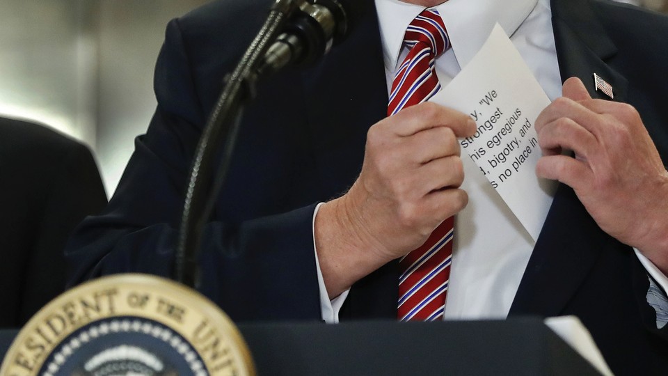 President Trump reaches for a prepared statement in his pocket