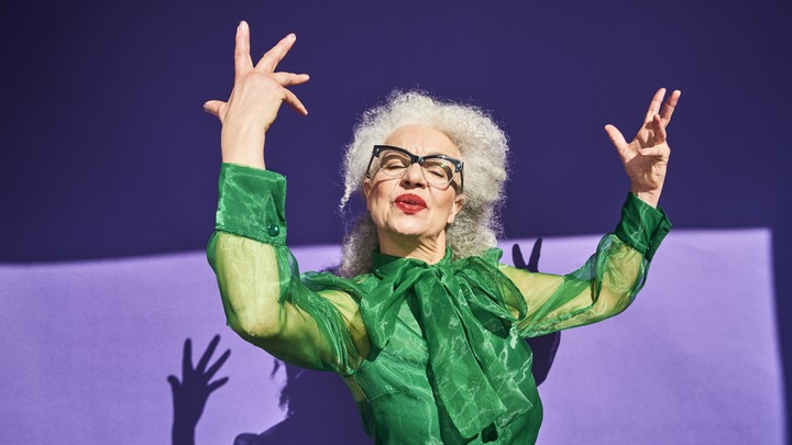 A confident-looking woman holds her arms in the air.