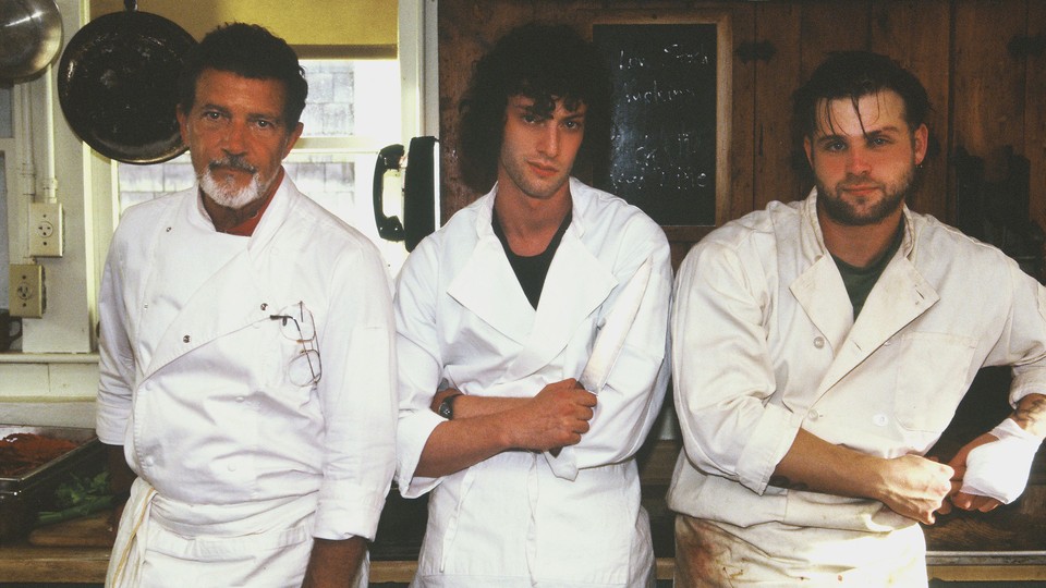 A photo of three men wearing white chef jackets in a restaurant kitchen