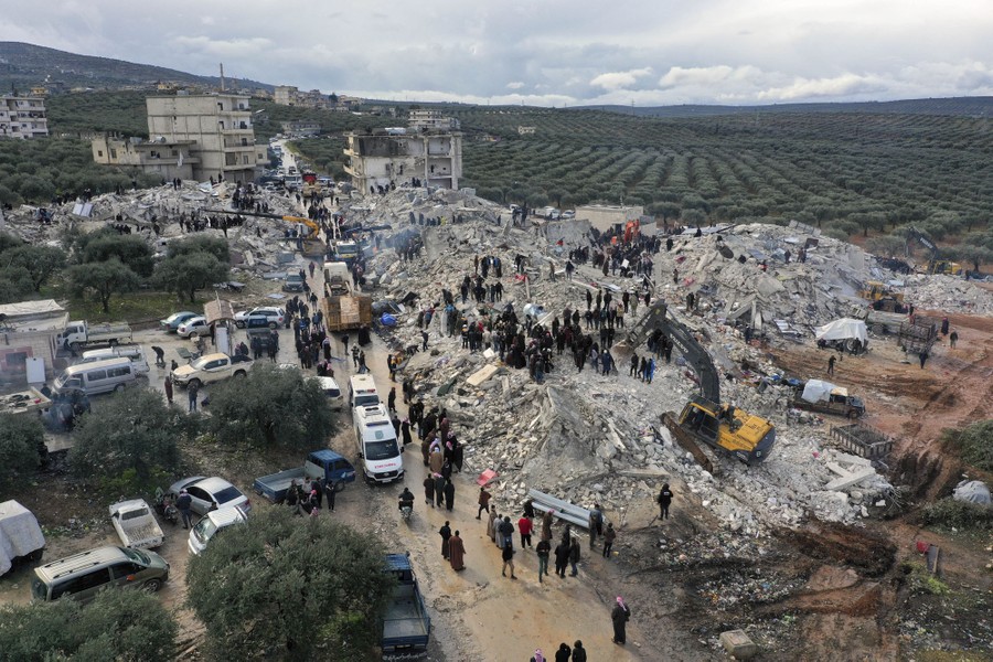 Rescue workers use construction equipment to try to clear piles of rubble from collapsed buildings.