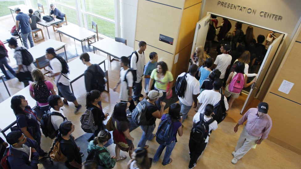 Students stand outside of a college lecture hall.