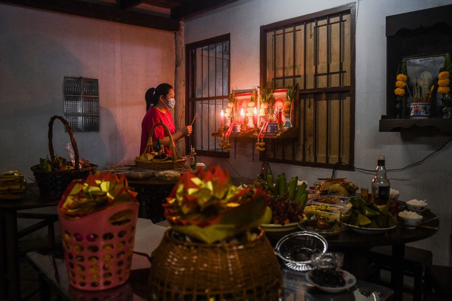 A person inside a room in their home offers prayers and gifts at a small altar.