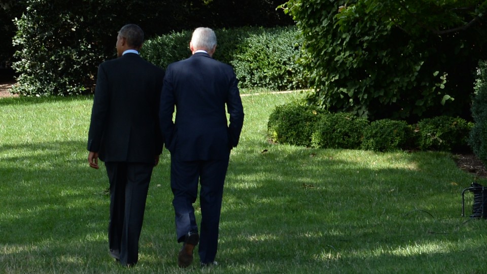 Former Presidents Barack Obama and Bill Clinton walk through a garden, facing away from the camera.