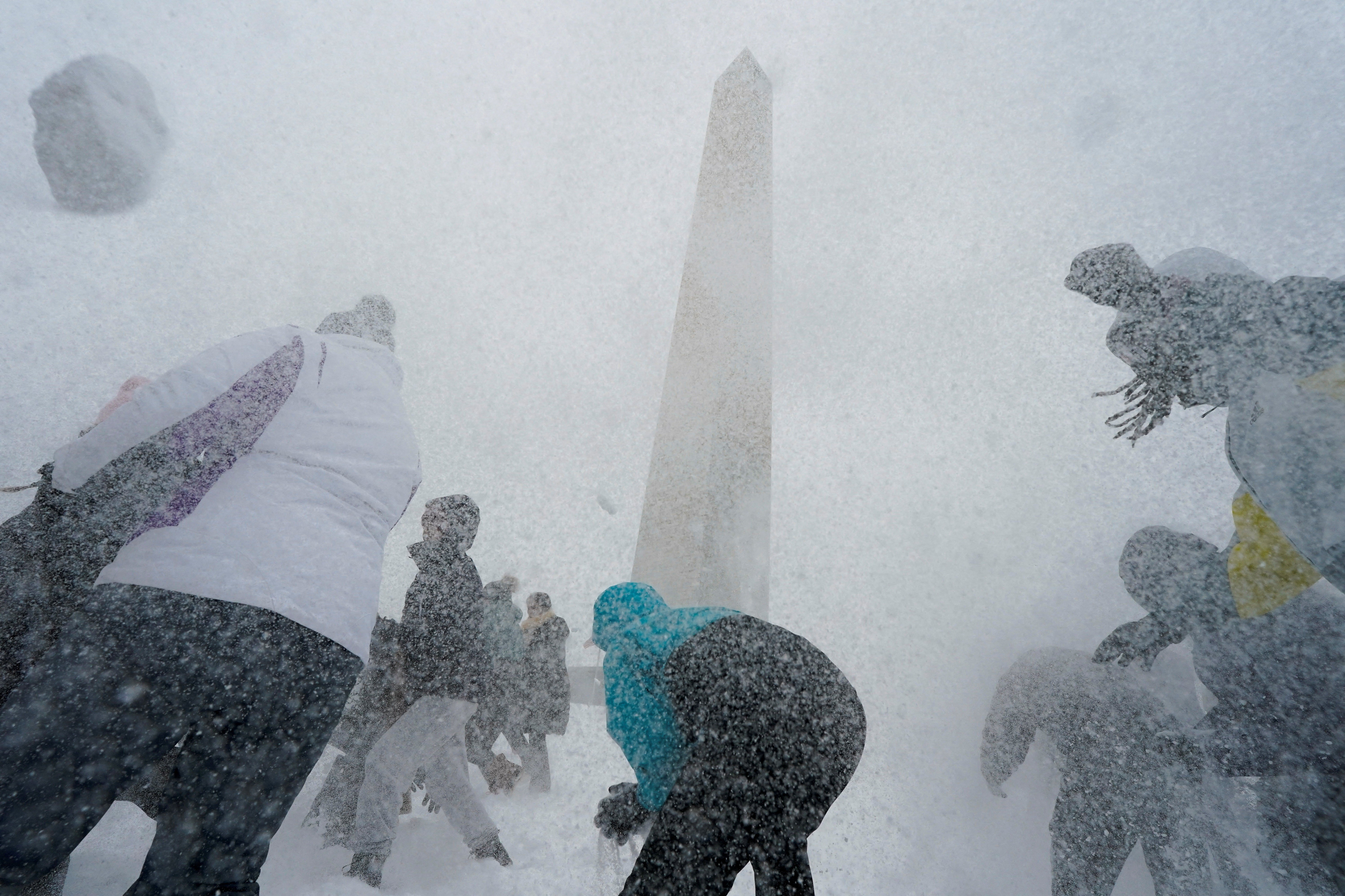 People play with snowballs by the Washington Monument during a snowfall.