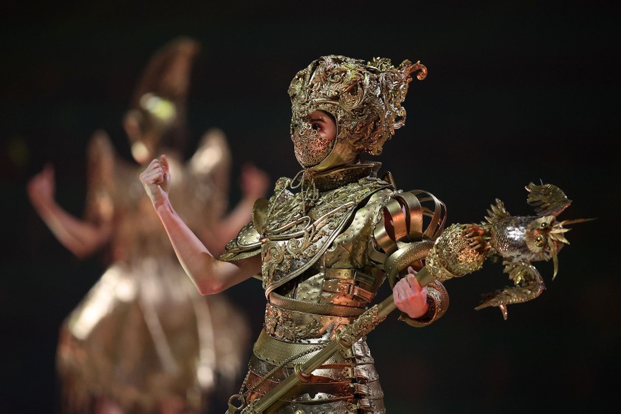 A model displays a garment that looks like ornate golden armor.