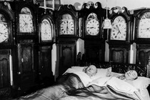 A couple sleeping, surrounded by clocks