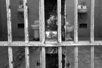 A black-and-white photo of prison cells behind bars