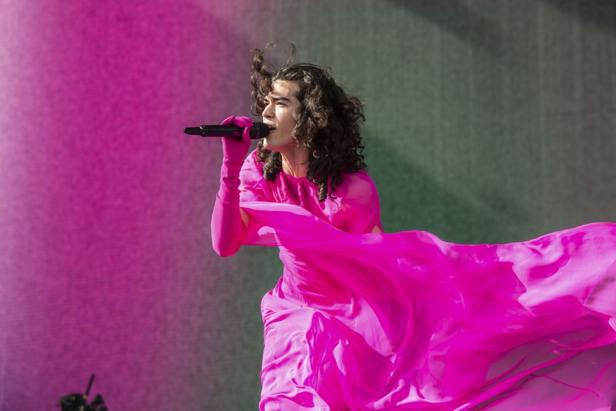 A performer wearing a long, flowing garment sings onstage.