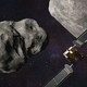 A spacecraft approaches two asteroids in a dark sky.