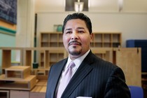 Man in suit with an empty classroom behind him