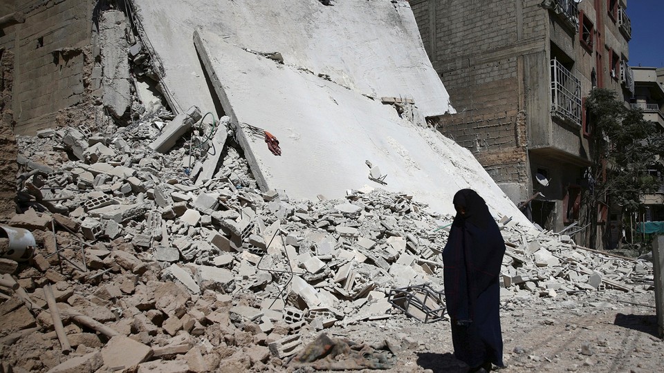 A woman walks past a damaged building after an airstrike in the rebel held Douma neighbourhood of Damascus.