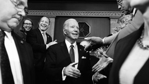 A black-and-white photo of Joe Biden shaking hands with members of Congress