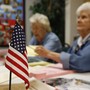An American flag sits on the table where two Oklahoma poll workers are helping voters.