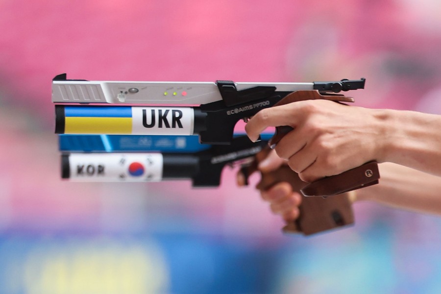 A close shot of two hands, each holding a modified laser pistol, marked with country names for a competition.