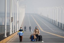 Mother and son with face masks approach a checkpoint.