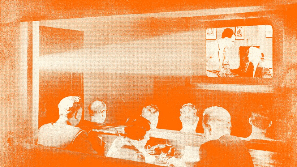 A vintage photo of people watching the projection of a movie in a theater