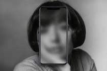 A black-and-white portrait of a woman with a phone over her face