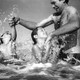 a man struggles as he plays with two children at the beach