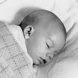 Black-and-white photograph of a baby sleeping under a blanket