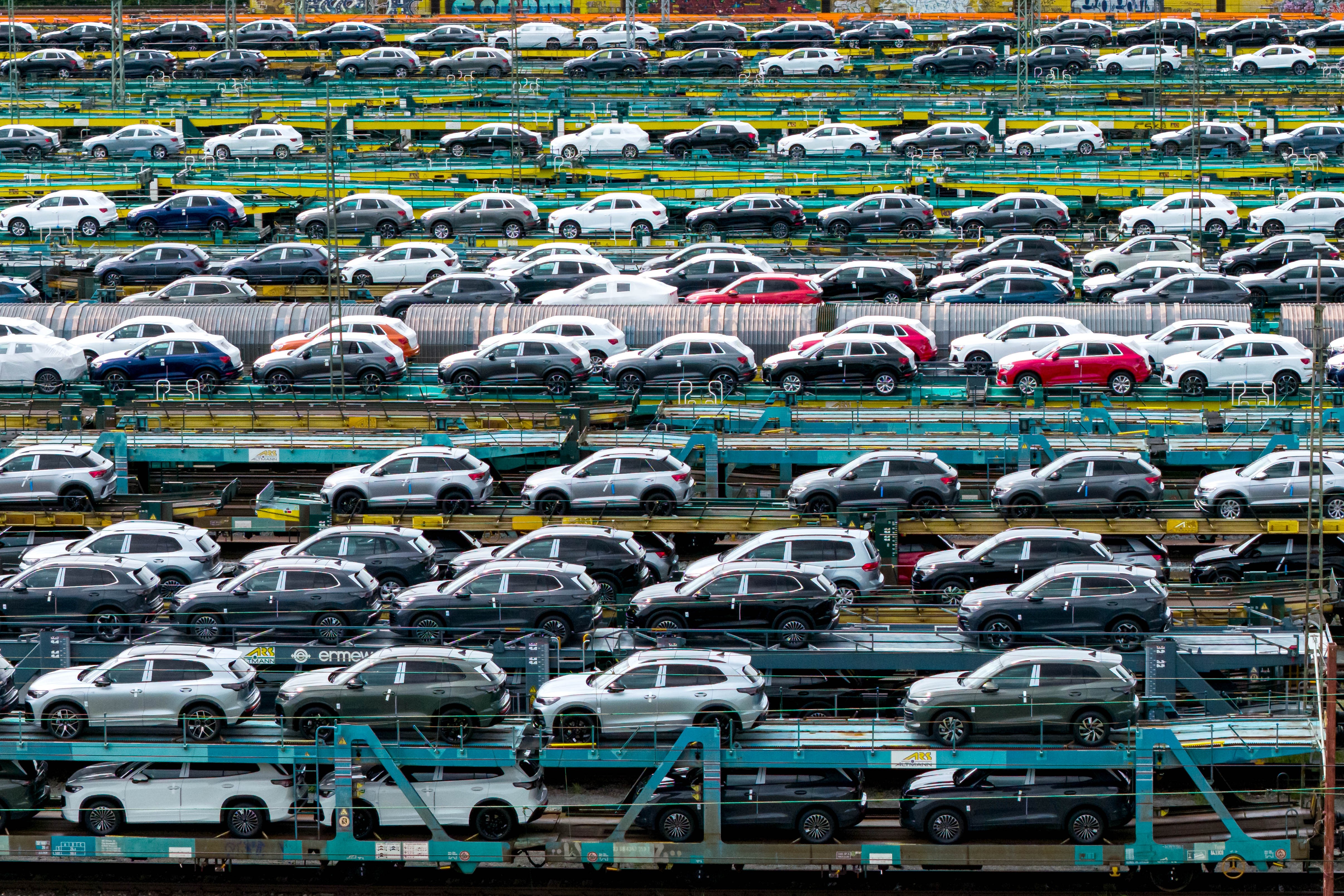 A view of many passenger cars parked on rail carrier cars.