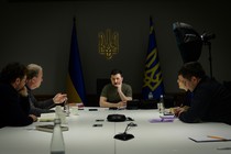 Jeffrey Goldberg and Anne Applebaum sit at a large table with President Volodymyr Zelensky and two other people.