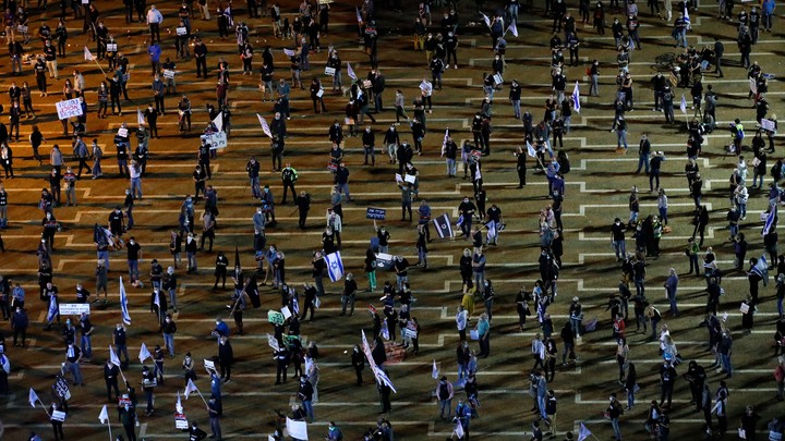 Israelis, keeping at a safe distance from one another, take part in a "Black Flag" demonstration, to protest against Prime Minister Benjamin Netanyahu and anti-democratic measures to contain the novel coronavirus outbreak, at Rabin Square in the coastal city of Tel Aviv, on April 19, 2020. (Photo by JACK GUEZ/AFP via Getty Images)