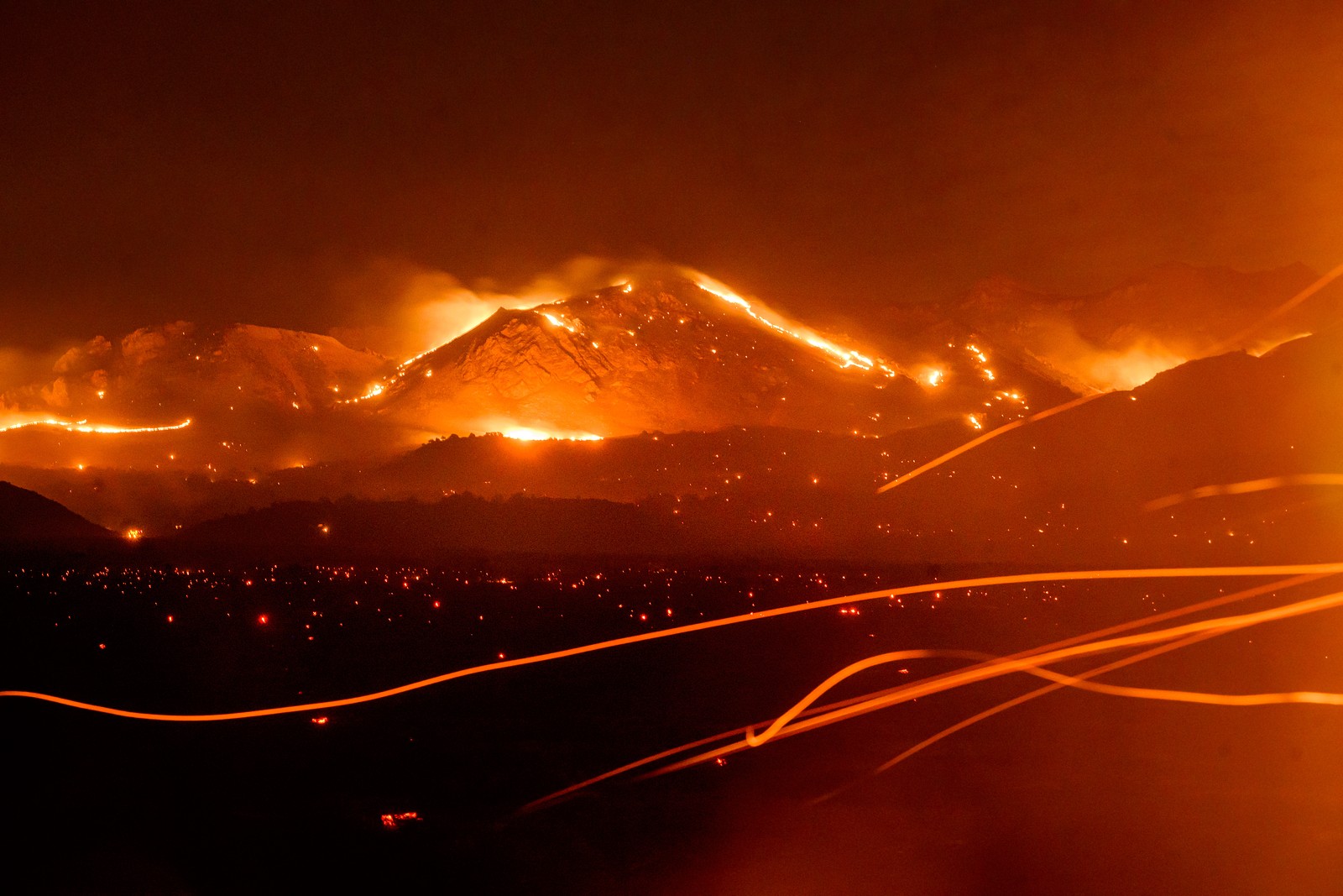 A long-exposure photo of wildfires burning across a mountainous area at night