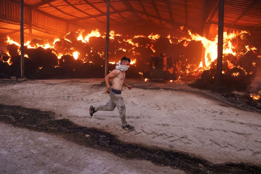 A young man runs past a burning barn.