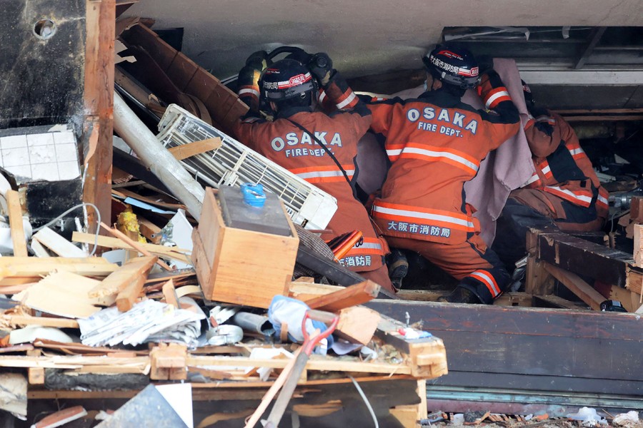 Several rescuers work inside the rubble of a collapsed building.
