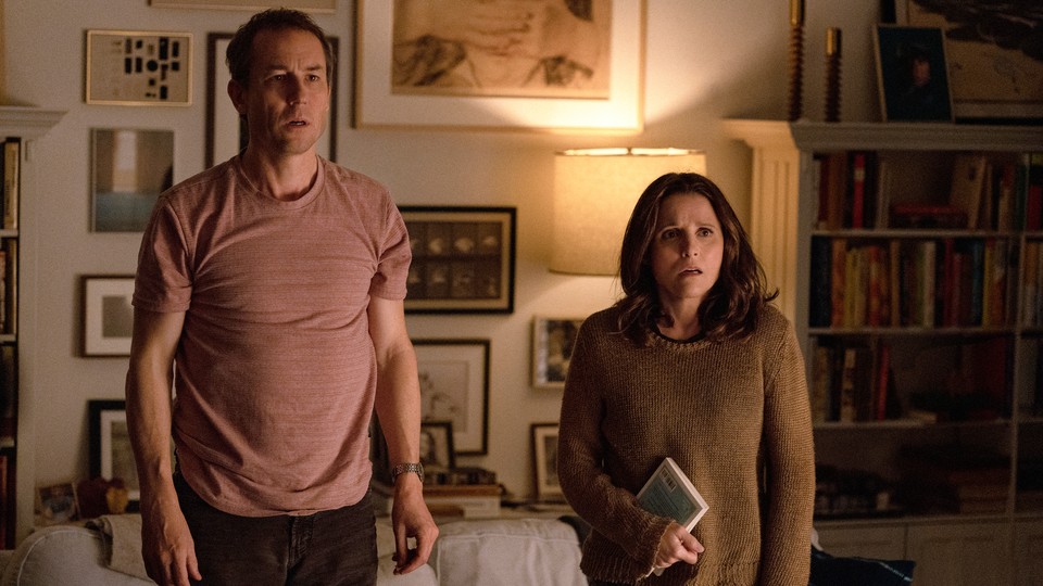Tobias Menzies and Julia Louis-Dreyfus standing in front of a living-room couch with appalled looks on their faces