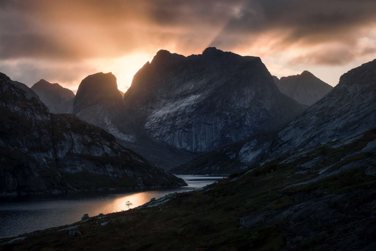 Low sunlight and clouds, above mountains and a body of water in a valley