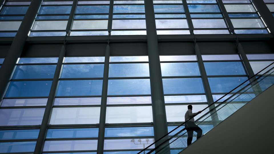 A man on an escalator looks at an enormous set of windows.