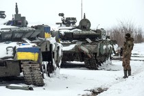 A photo of a Ukrainian soldier standing beside tanks